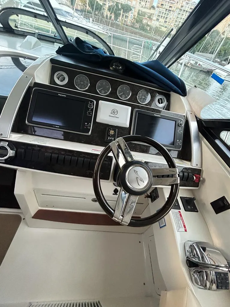 Slide: The Image of 2013 Sea Ray 410 Sundancer helm with modern navigation controls and sleek steering wheel. - 6