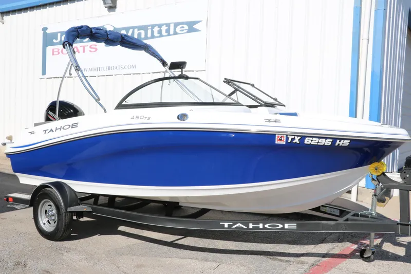 Slide: The Image of 2020 Tahoe 450 TS boat on trailer, blue and white, parked outside dealership. - 1