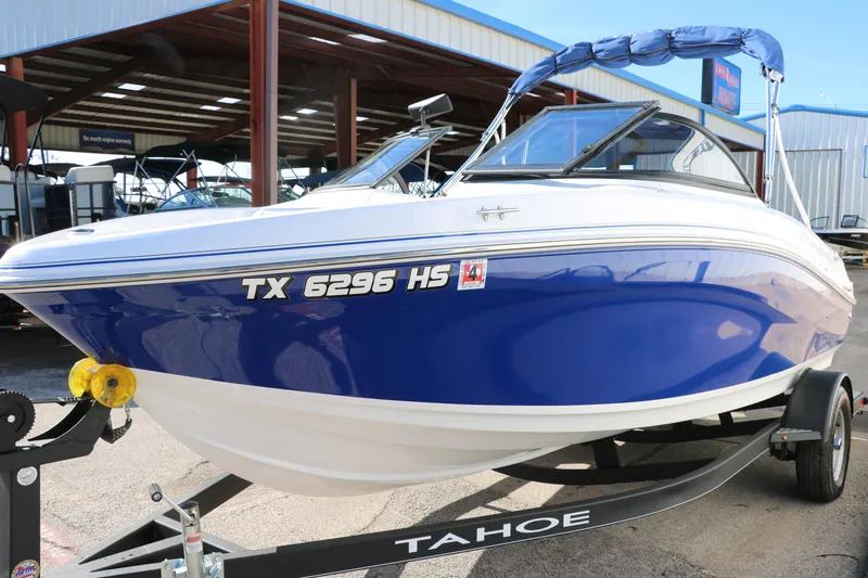 Slide: The Image of 2020 Tahoe 450 TS boat on trailer, blue and white, parked at a marina. - 9