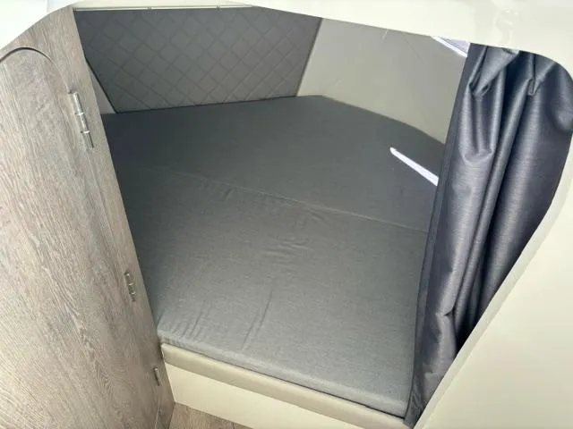 Slide: The Image of 2024 Bayliner TROPHY 25 EXPLORER cabin interior with bed and privacy curtain. - 13