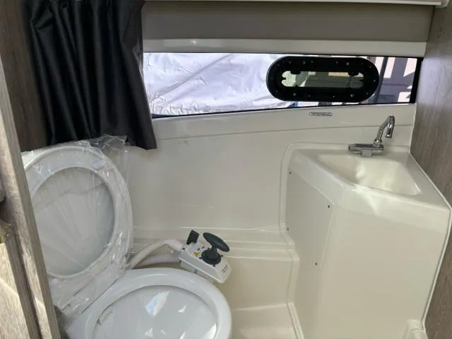 Slide: The Image of 2024 Bayliner TROPHY 25 EXPLORER boat bathroom with toilet, sink, and window. - 19
