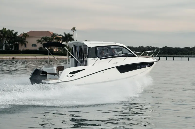 Slide: The Image of 2024 Bayliner TROPHY 25 EXPLORER cruising on water near a coastal residence. - 32