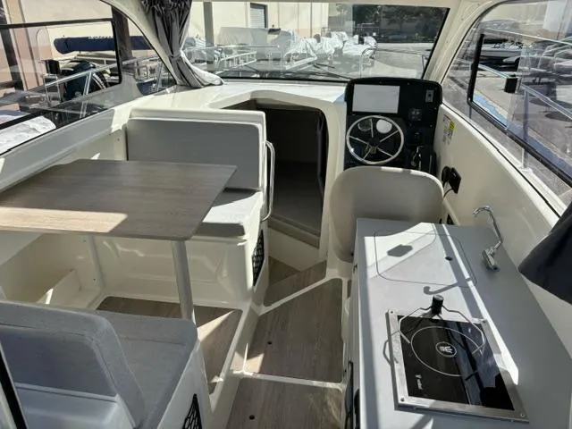 Slide: The Image of 2024 Bayliner TROPHY 25 EXPLORER boat interior with seating, table, and kitchenette. - 7