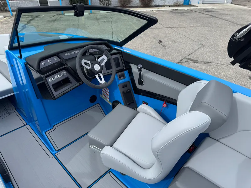 Slide: The Image of 2024 MasterCraft NXT23 boat interior with blue and gray seating and modern dashboard. - 10