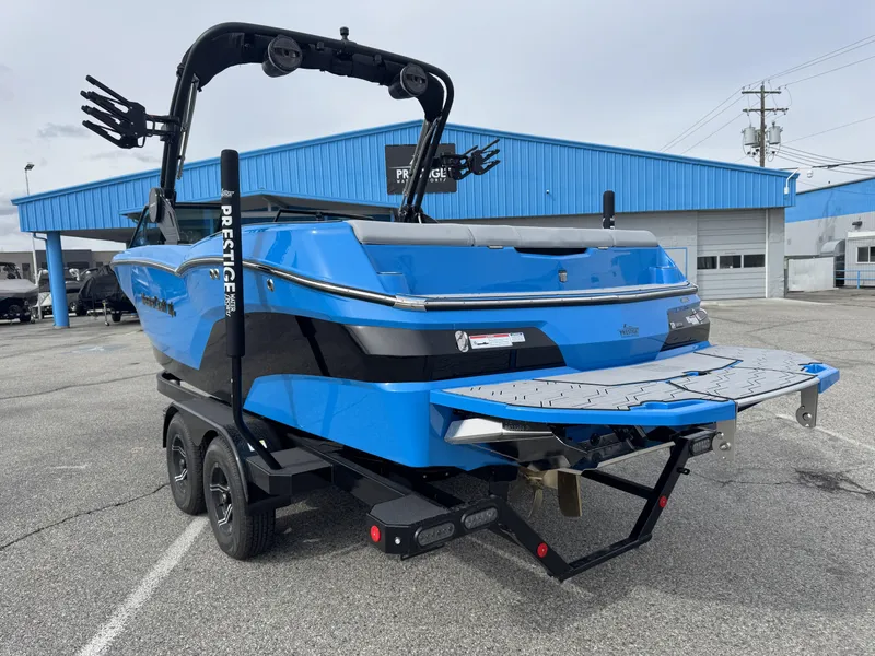 Slide: The Image of 2024 MasterCraft NXT23 boat in vibrant blue on a trailer, parked outside a dealership. - 4