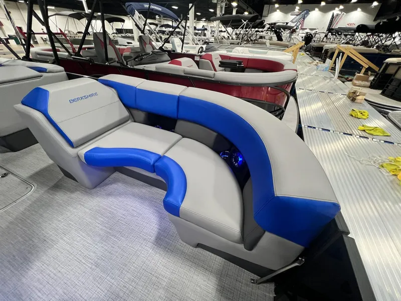 Slide: The Image of 2024 Berkshire 25RFC STS pontoon boat with blue and gray seating at a boat show. - 8