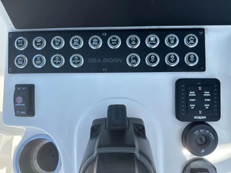 Slide: The Image of Control panel of a 2024 Sea Born FX25 Bay boat with various switches and controls. - 34
