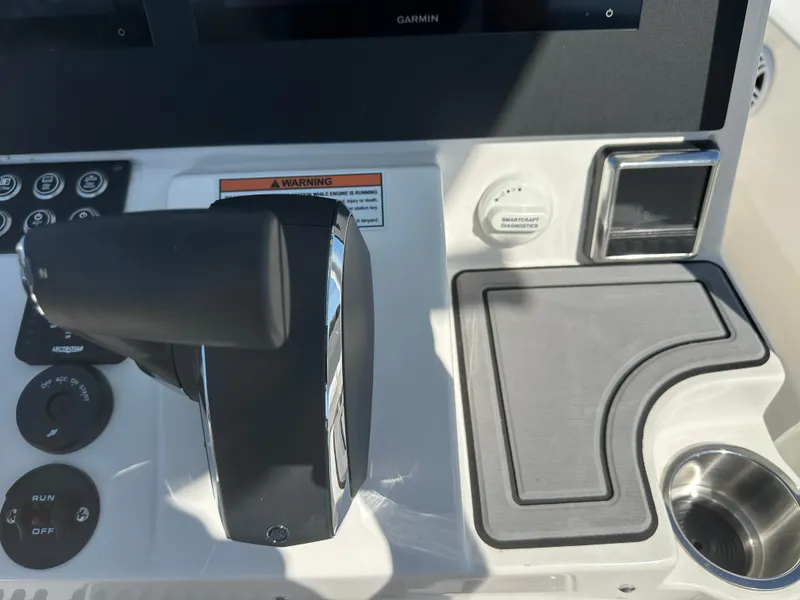 Slide: The Image of 2024 Sea Born FX25 Bay boat control panel with throttle, cup holder, and navigation system. - 35