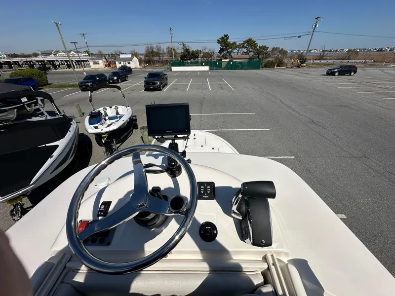 Slide: The Image of 2024 Sea Born FX25 Bay boat dashboard with steering wheel and navigation screen in a parking lot. - 45