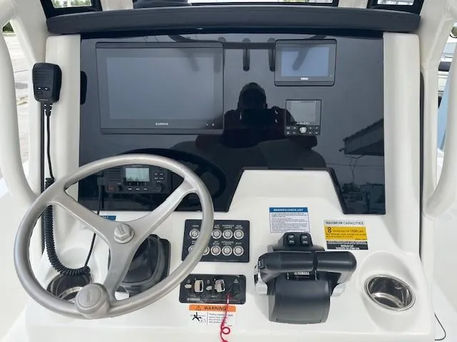 Slide: The Image of 2024 World Cat 235 CC boat dashboard with steering wheel, controls, and navigation screens. - 7