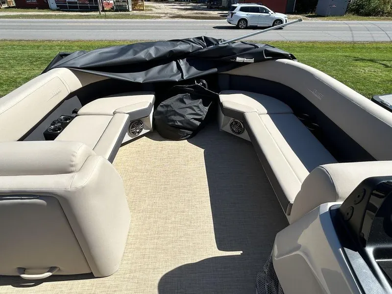 Slide: The Image of 2024 Harris Cruiser 230 boat interior with beige seating and black cover. - 13