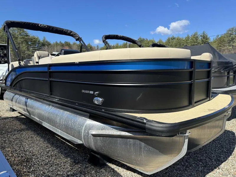 Slide: The Image of 2024 Harris Cruiser 230 pontoon boat with sleek black and blue design, parked outdoors. - 2