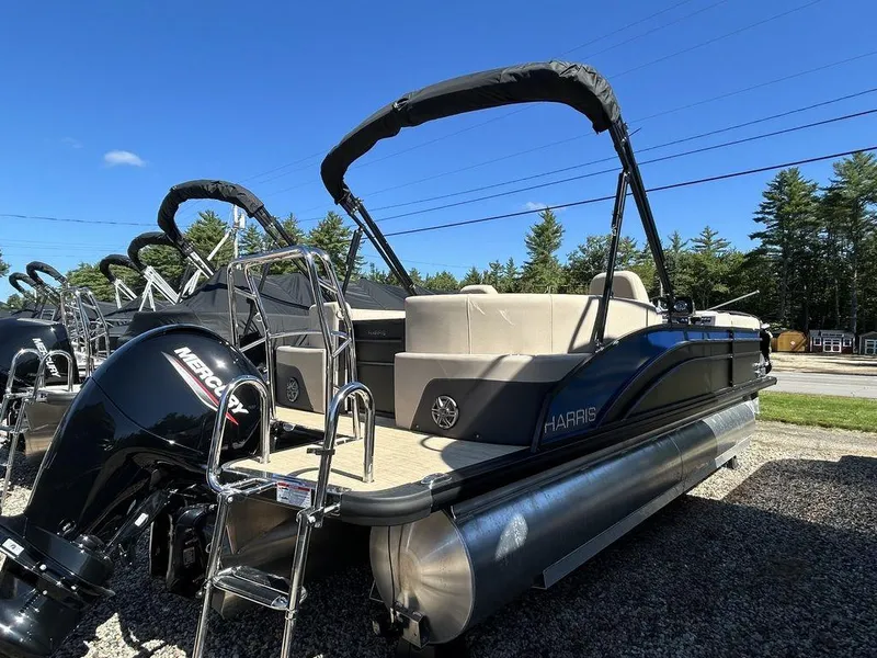 Slide: The Image of 2024 Harris Cruiser 230 pontoon boat with Mercury engine, parked outdoors under clear blue sky. - 4