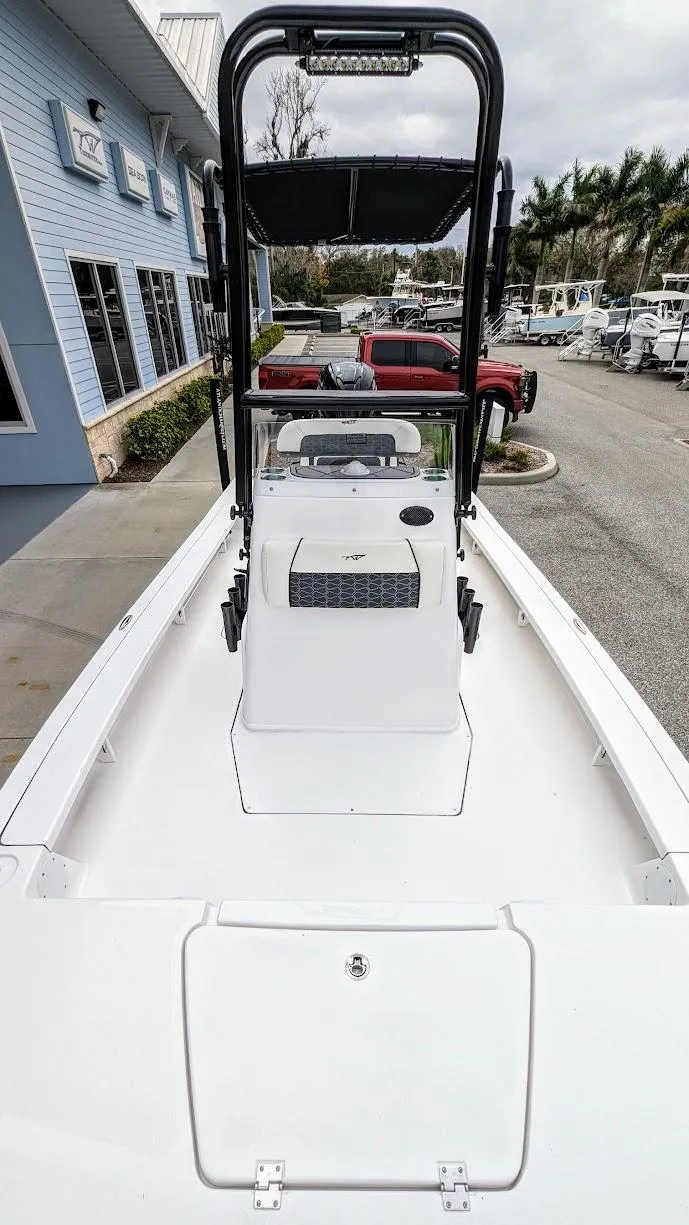 Slide: The Image of 2024 Tidewater 23 TPC Raptor boat, white deck, center console, docked near blue building. - 17