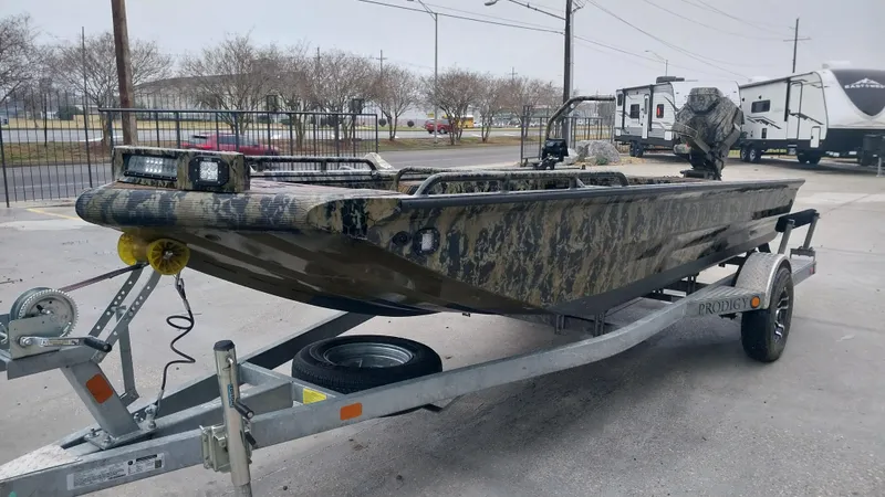 Slide: The Image of 2022 Prodigy 18x60 Marsh Tuff boat on trailer, camo design, parked outdoors. - 10