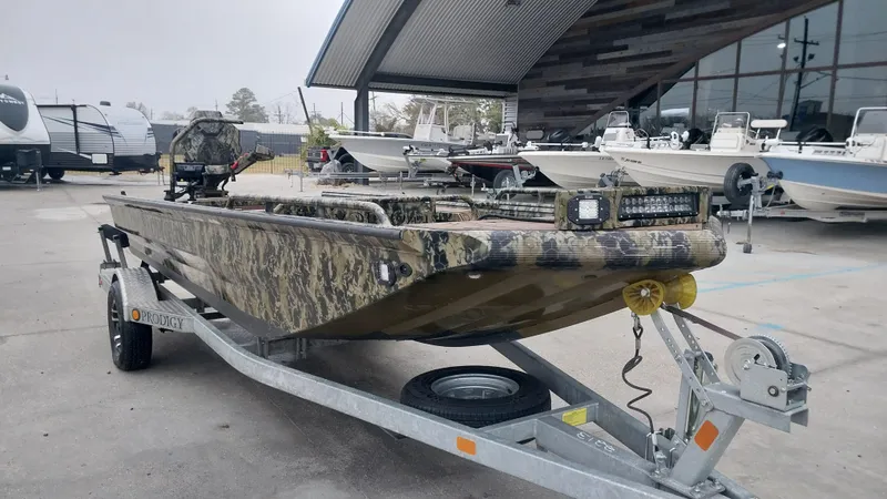 Slide: The Image of 2022 Prodigy 18x60 Marsh Tuff boat on trailer, camo design, parked at dealership. - 9