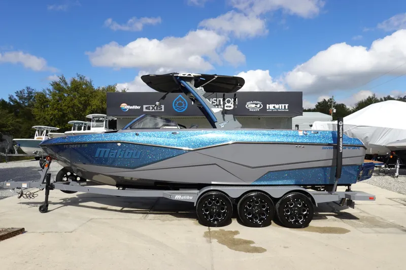 The Image of 2023 Malibu 25 LSV boat on a trailer, displayed outdoors under a blue sky. - 0