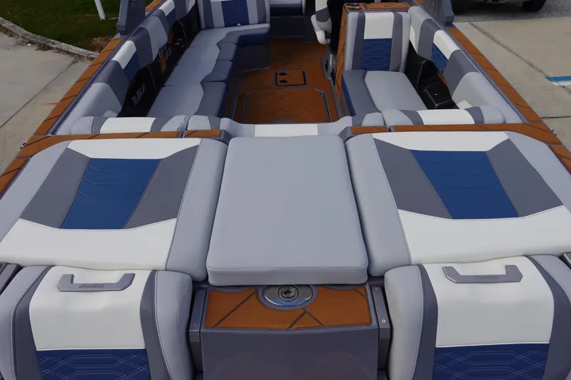 Slide: The Image of 2023 Malibu 25 LSV boat interior with gray, blue, and white cushioned seating. - 11