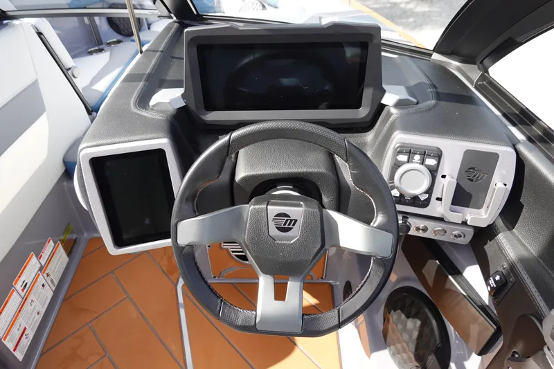 Slide: The Image of 2023 Malibu 25 LSV boat dashboard with steering wheel and digital displays. - 15