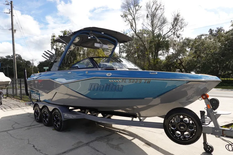 Slide: The Image of 2023 Malibu 25 LSV boat on trailer, blue and gray exterior. - 2