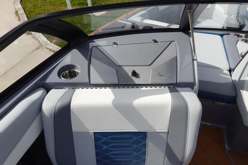 Slide: The Image of 2023 Malibu 25 LSV boat interior with gray and white seating and storage compartment. - 23