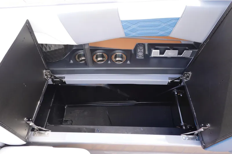 Slide: The Image of Open storage compartment in 2023 Malibu 25 LSV boat with cup holders and accessory slots. - 32