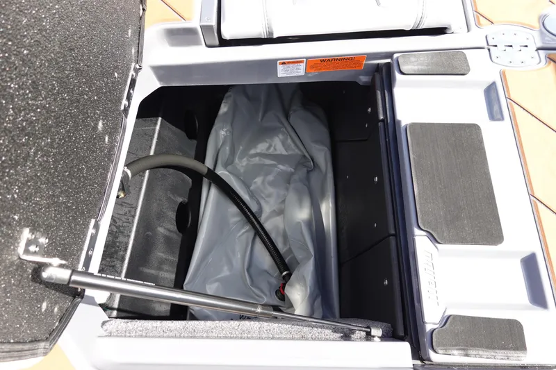 Slide: The Image of Open storage compartment of 2023 Malibu 25 LSV boat with hose and cover. - 44