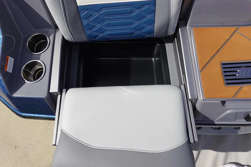 Slide: The Image of 2023 Malibu 25 LSV boat interior storage compartment with cup holders and cushioned seating. - 9