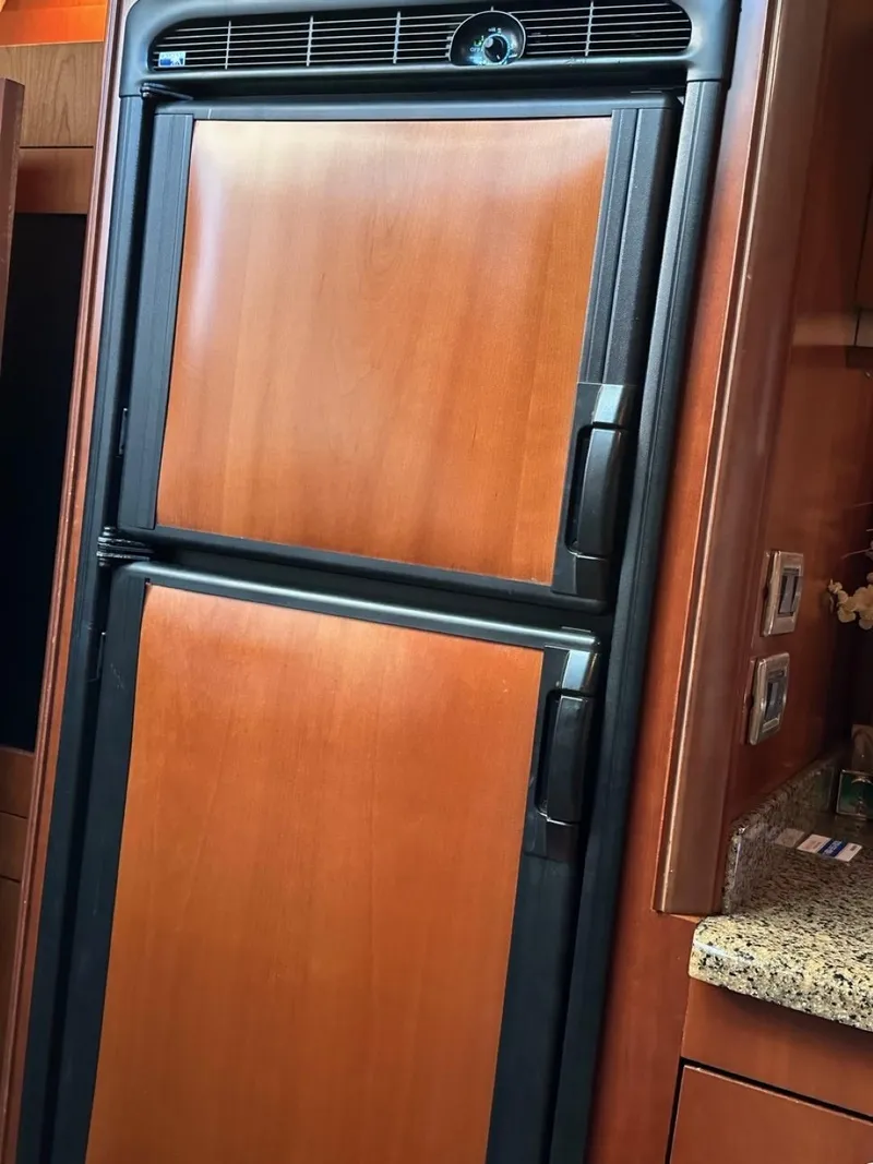 Slide: The Image of 2006 Sea Ray 48 Sundancer yacht kitchen with wood-paneled refrigerator and granite countertop. - 9