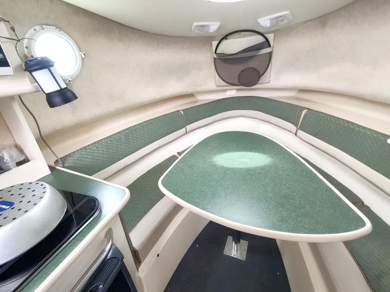 Slide: The Image of 2003 Trophy 2902 Walkaround cabin interior with green table and compact kitchen. - 9