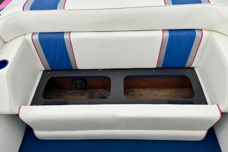 Slide: The Image of 1994 Howard 22 Bowrider boat seat with blue and pink accents, open storage compartment. - 17