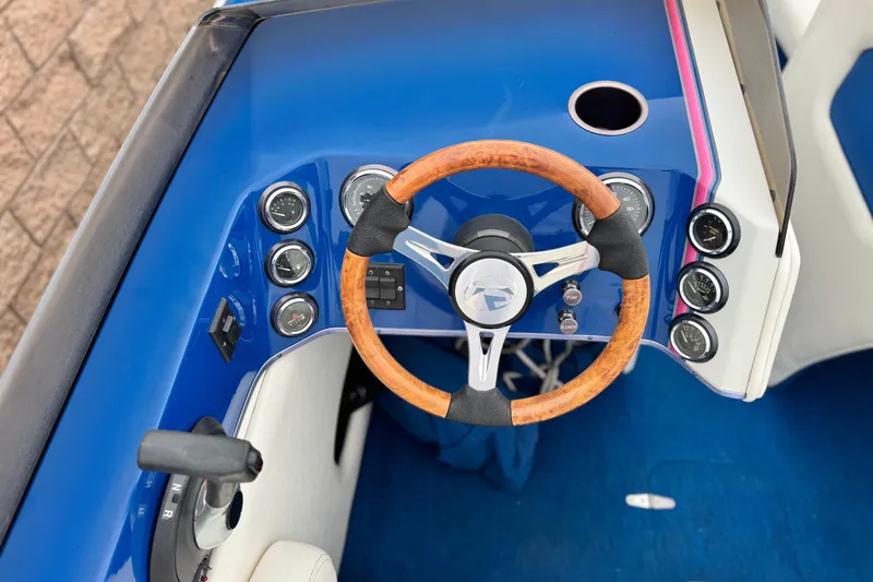Slide: The Image of 1994 Howard 22 Bowrider dashboard with wooden steering wheel and gauges. - 22