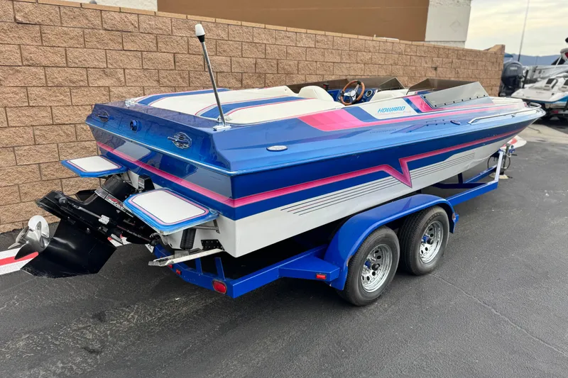 Slide: The Image of 1994 Howard 22 Bowrider boat with vibrant blue and pink design on trailer. - 5