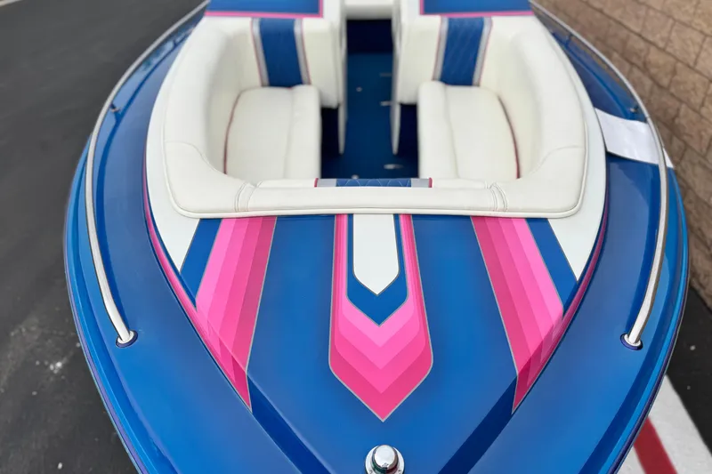 Slide: The Image of 1994 Howard 22 Bowrider boat with vibrant blue and pink design, white seating. - 9