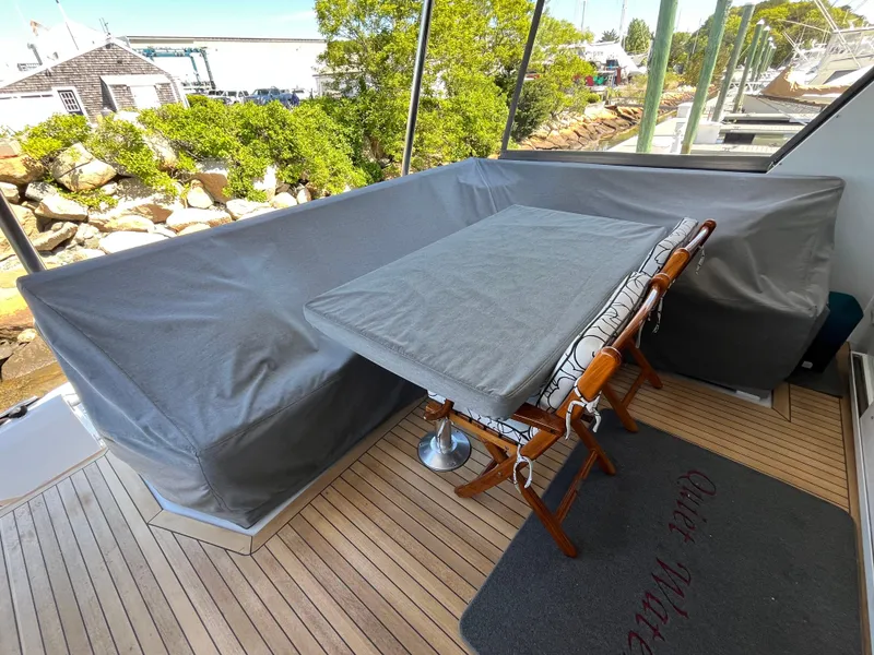 Slide: The Image of 1999 Hatteras 74 Sport Deck Motor Yacht covered outdoor seating area with table and chairs. - 12