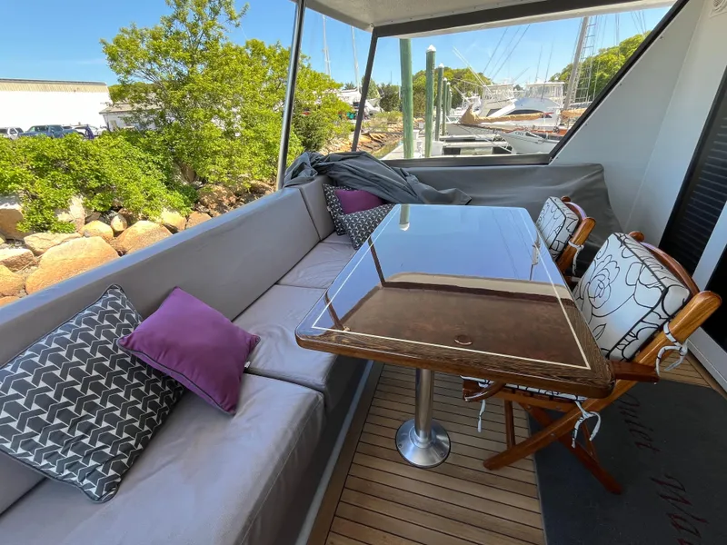 Slide: The Image of 1999 Hatteras 74 Sport Deck Motor Yacht outdoor seating area with table and cushions. - 16