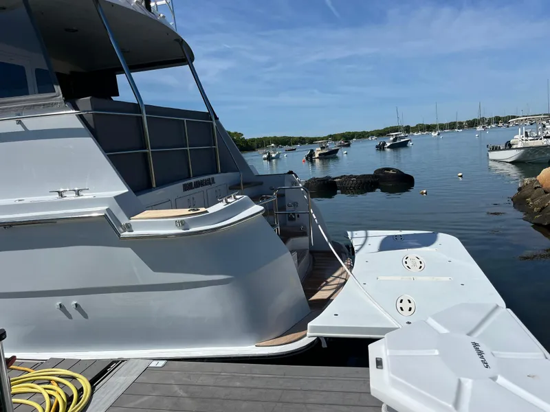 Slide: The Image of 1999 Hatteras 74 Sport Deck Motor Yacht docked in a serene marina. - 5