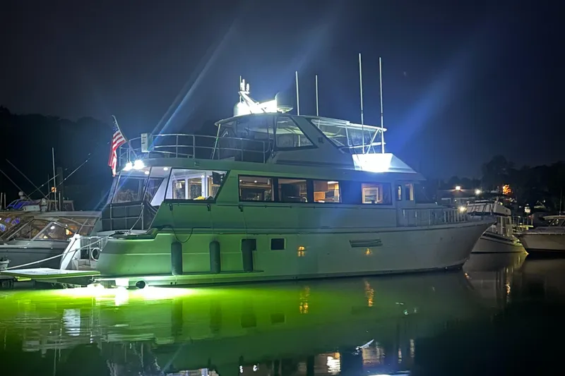 Slide: The Image of 1999 Hatteras 74 Sport Deck Motor Yacht illuminated at night, docked with glowing water reflection. - 7