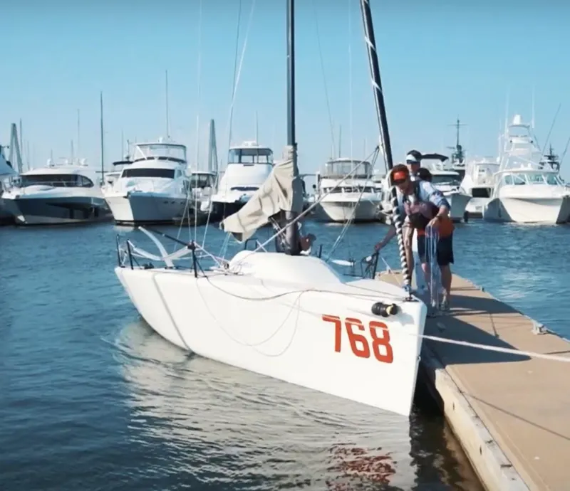 The Image of 2009 Melges 24 sailboat docked at marina with people on board. - 1