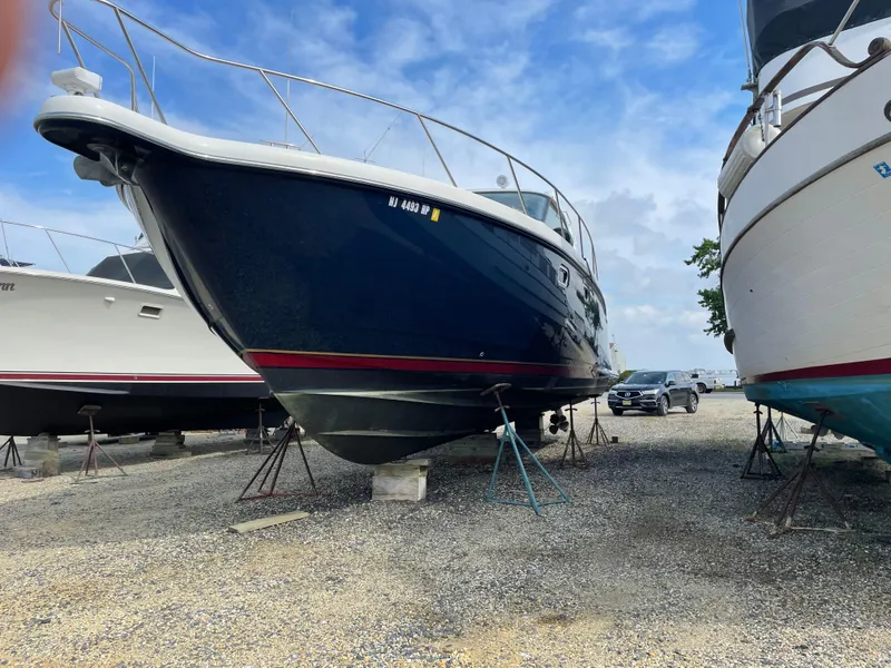 Slide: The Image of 2008 Tiara Yachts 4300 Sovran on dry dock, blue hull, gravel lot, clear sky. - 1