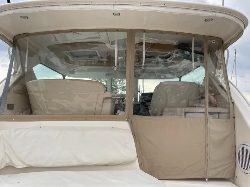 Slide: The Image of 2008 Tiara Yachts 4300 Sovran cockpit with beige seating and clear enclosure. - 11