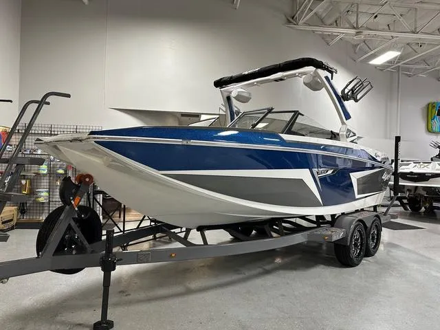 Slide: The Image of 2024 Tigé 22RZX boat in showroom, blue and white design on trailer. - 3