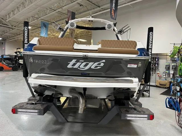 Slide: The Image of 2024 Tigé 22RZX boat displayed in showroom, rear view with seating and branding. - 5