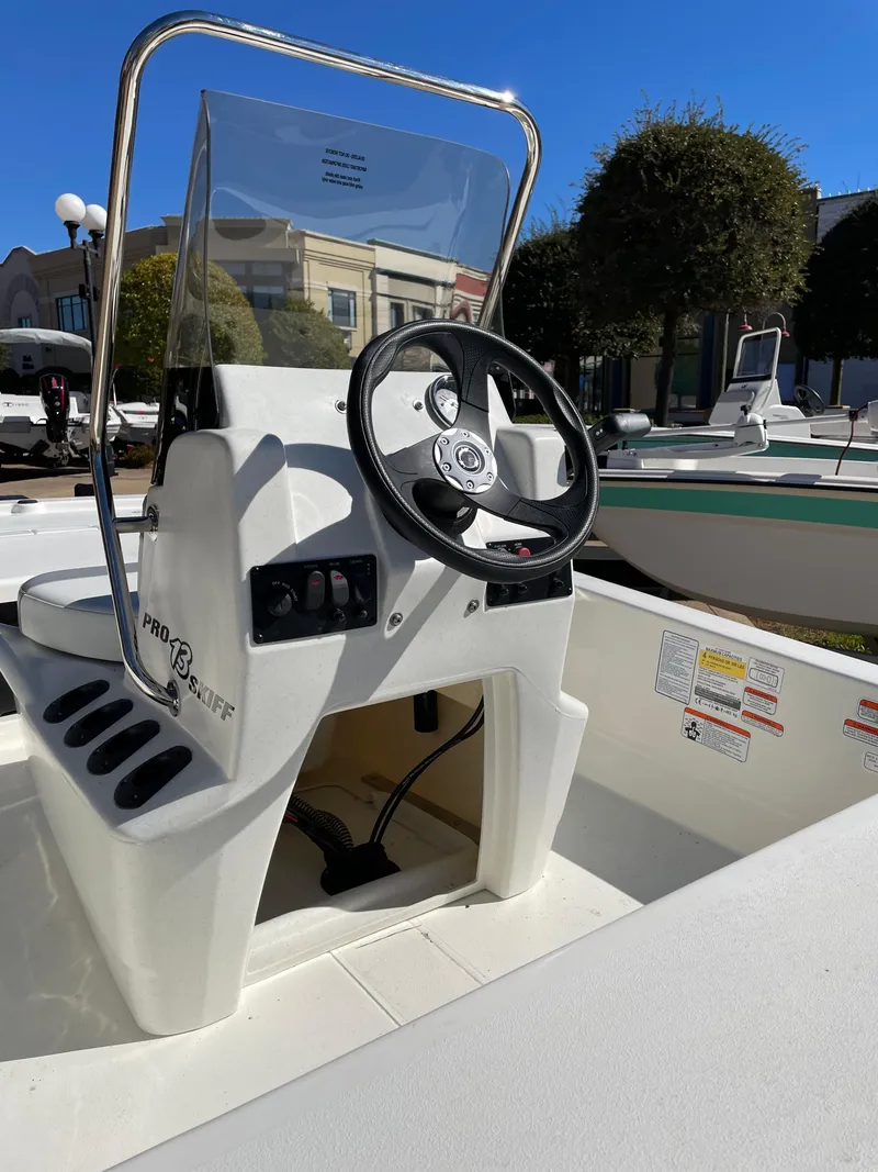 Slide: The Image of 2024 Mako Pro Skiff 13 CC center console boat with steering wheel and controls. - 5