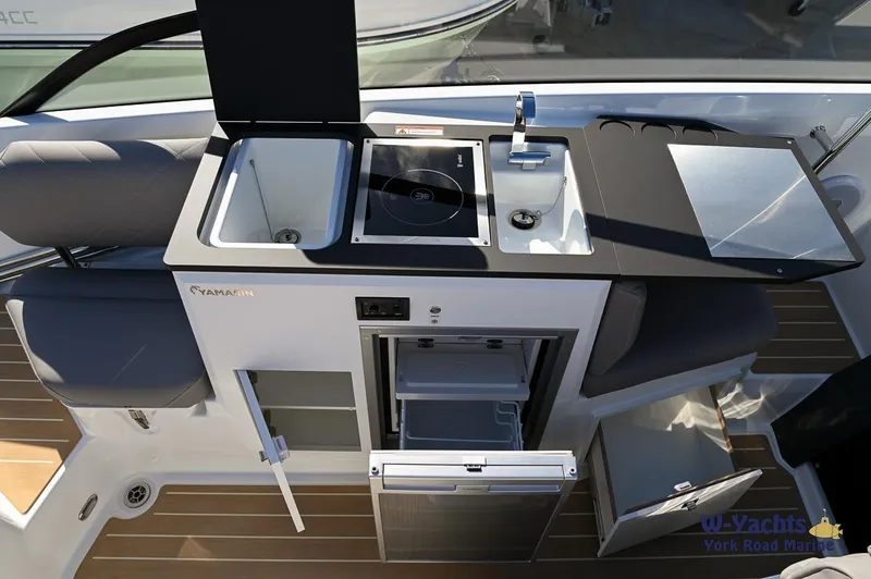 Slide: The Image of 2024 Yamarin 80 boat kitchen area with sink, stove, and storage compartments. - 25