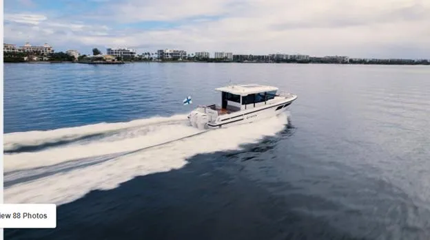 Slide: The Image of 2025 Quarken 35 boat cruising on a calm lake with cityscape in the background. - 3