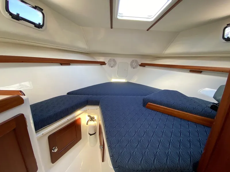 Slide: The Image of 2022 NorthCoast 315 boat cabin with blue bedding and wooden accents. - 18