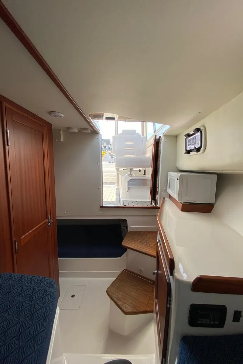 Slide: The Image of 2022 NorthCoast 315 boat interior with wooden accents and seating area. - 20
