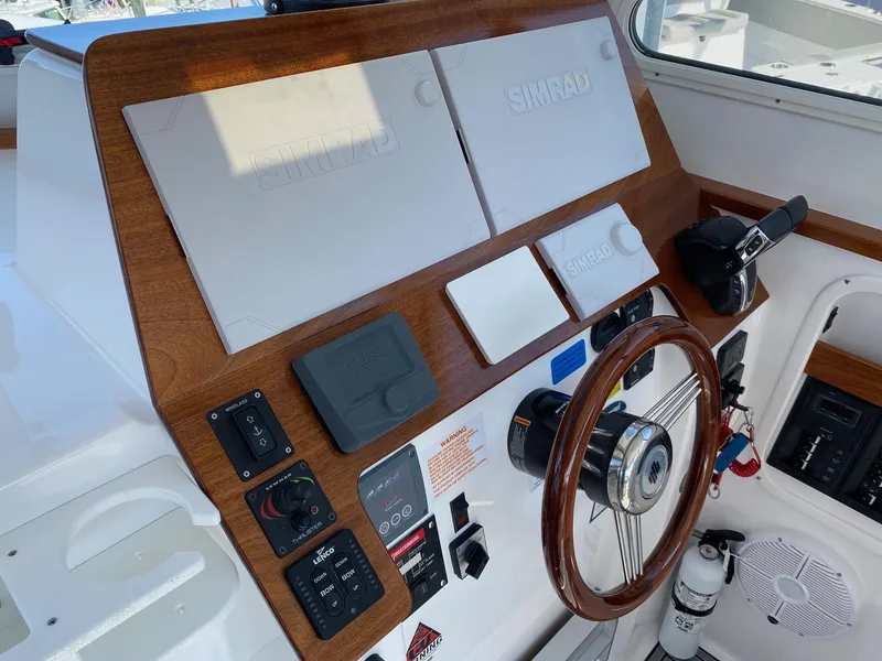 Slide: The Image of 2022 NorthCoast 315 boat helm with wooden dashboard, steering wheel, and control panels. - 10