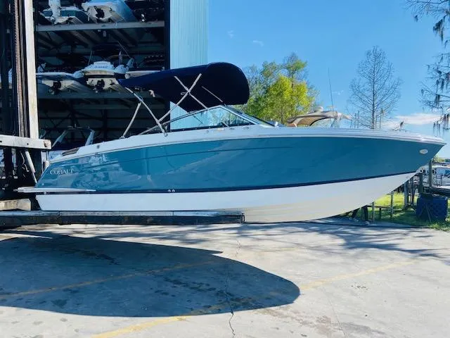 Slide: The Image of 2023 Cobalt R6 boat with blue hull and black bimini top in storage facility. - 2